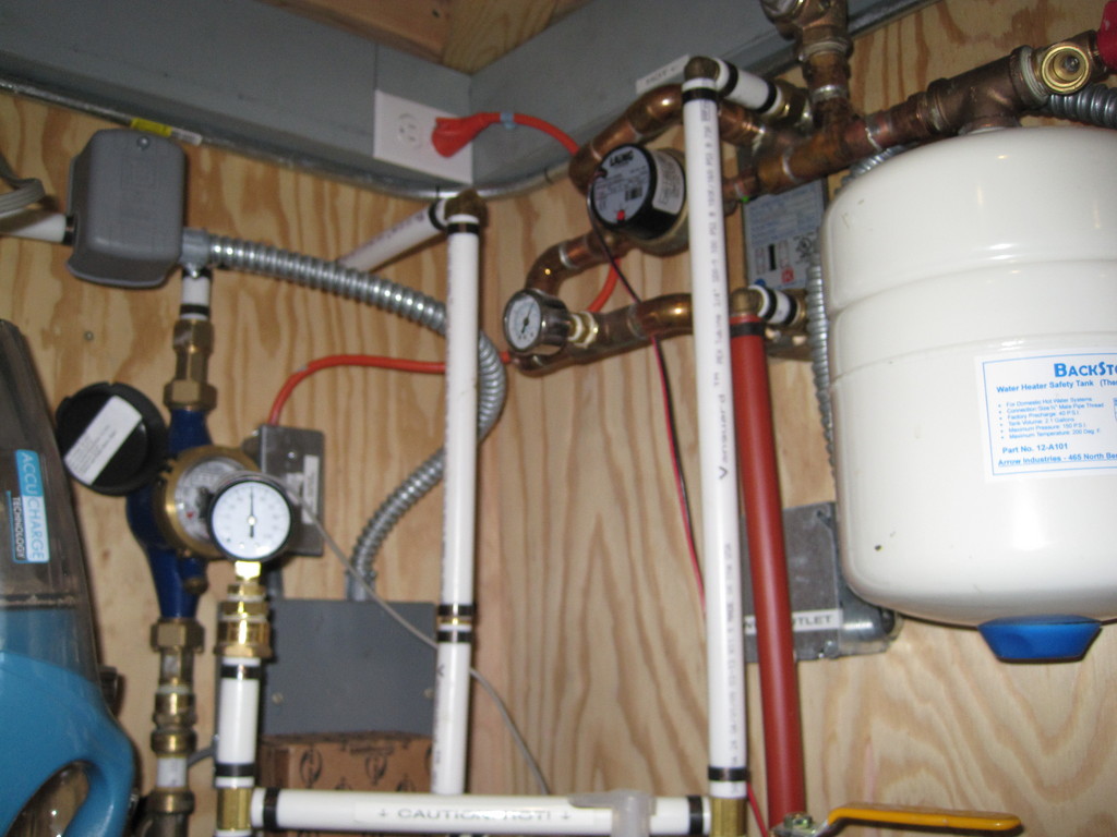 Fuzzy picture of flat plate heat exchanger, expansion tank, glycol circulation pump, water meter, and water pressure gauge.