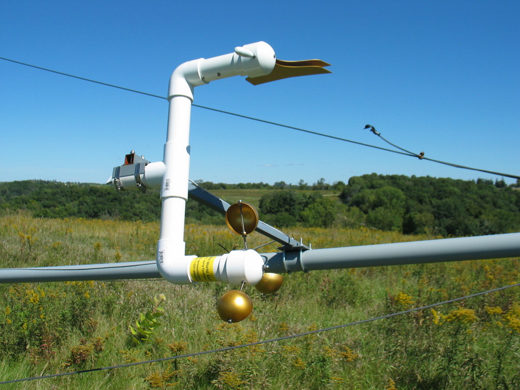 Anemometer, wind vane, tee, and mounting arm on tilted over tower. The tee is held into the mounting arm using standard hose clamps (not included) and the mounting arm is attached to the tower with 3/8" u-bolts (also not included).