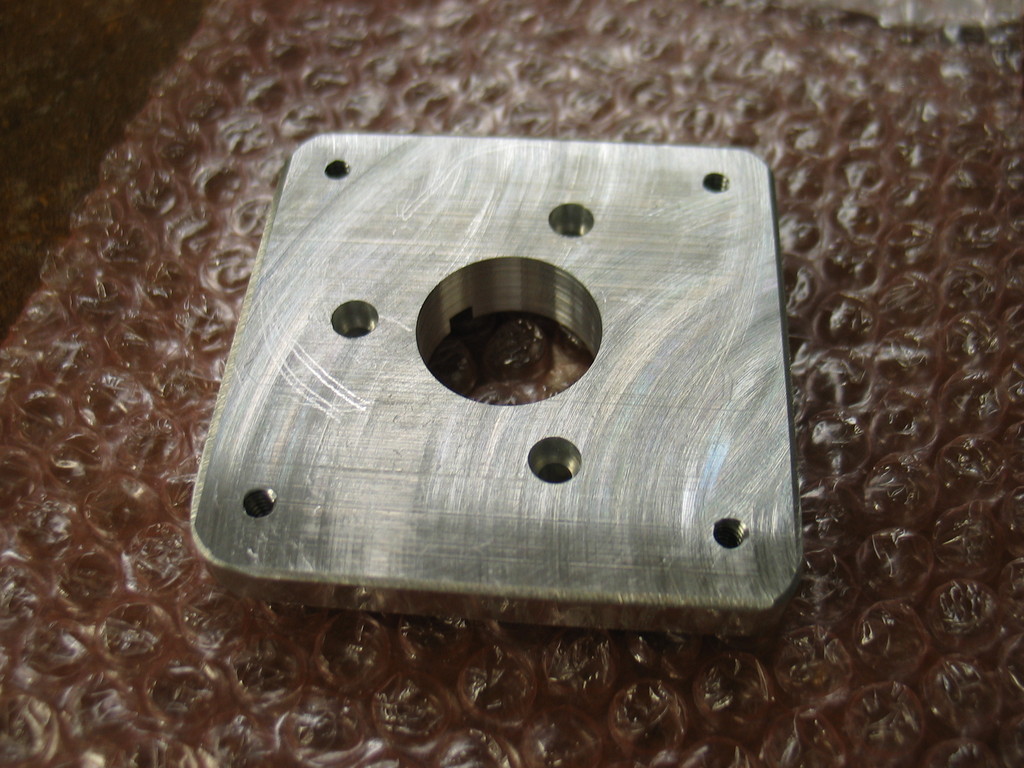 The counterbored holes are for #8-32 screws that go to the motor gear box. I finally used my counterbore drill bit set. It's incrediby fast to use. For a one off like this it is easier than loading a end mill in to the CNC mill and cutting a circular pocket.

The adapter is machined from 3x3x1/2" 6061-T6. I chopped sawed it to size and then drill the holes and milled the circular frame on the CNC mill. Deburring was done on the new disc sander.
