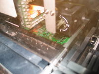 The pick and place machine has vacuum heads that suck the tiny SMT parts off the reel and then place them very accurately on the circuit board.