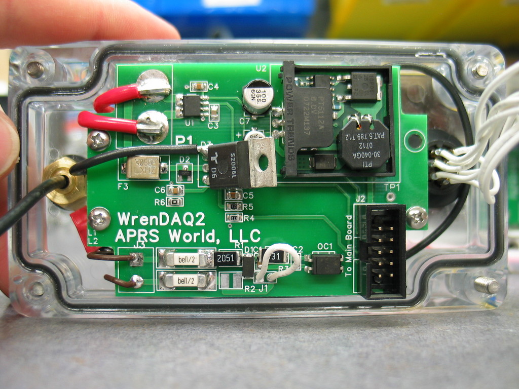 One of two WrenDAQ2 circuit boards. This board has a current sensor (marked U1), a switching power supply module (marked U2), crowbar over voltage protection, and a AC frequency pickup. It connect to the other circuit board with a 10 pin ribbon cable plugged in to J2. The brass hardware on the left attaches the 900 MHz antenna. The white wires on the right are to the weatherproof sensor connector.